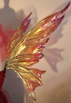 a mannequin dressed in red and gold with wings on it's head