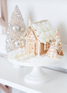 a small gingerbread house on a white cake plate