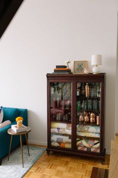 a living room with a blue couch and a glass cabinet filled with items on top of it