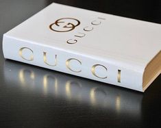 a book with the word gucci on it sitting on a table next to a pen