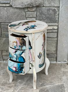 this is an image of a painted cabinet on the ground in front of a stone wall