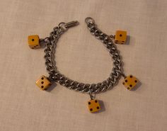 a chain bracelet with yellow dices on it and two small ones hanging from the clasp