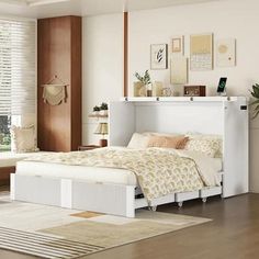 a white bed sitting next to a window on top of a wooden floor in a bedroom