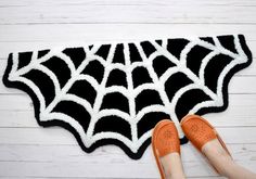 a woman's feet are shown next to a black and white spider web rug