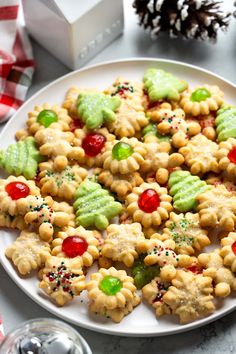 a white plate topped with cookies covered in candy and candies next to a christmas tree