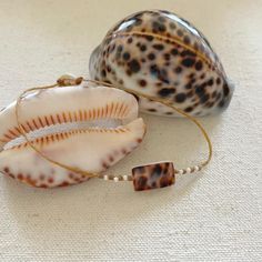 These beautiful tiger cowrie pieces are fused with mother of pearl so both sides are gorgeous. They are accented with freshwater seed pearls and woven onto braided waxed cord. Waxed cord is strong and waterproof🌊 Perfect for women with an active lifestyle.🧜🏻‍♀️ The cowrie pieces measure 5/8" by 3/8". Finished with a mother of pearl button clasp. Cowrie shells are from nature so each piece will be slightly different and unique.﻿💙Handmade by me with love in coastal Southern Maryland.💙Carefull Bohemian Shell With Adjustable Cord As Gift, Handmade Beige Bracelets For Vacation, Spiritual Beaded Bracelets With Sliding Knot For Beach, Adjustable Handmade Beaded Bracelets For Beach Season, Handmade Casual Shell Jewelry, Handmade Artisan Beaded Bracelets For Beach, Artisan Handmade Beaded Bracelets For Beach, Bohemian Beaded Bracelets With Adjustable Cord For Vacation, Bohemian Beaded Bracelet With Adjustable Cord For Vacation