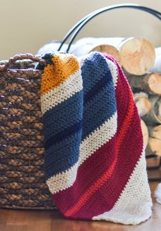 a basket with a blanket on top of it next to firewood logs and blankets