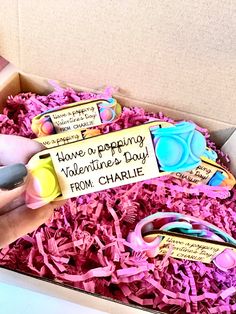 someone is holding a valentine's day card in a box filled with pink shredded paper