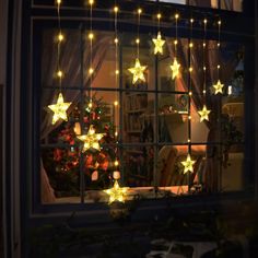 a window with christmas lights hanging from it's sides and stars on the windowsill