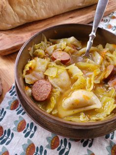 a wooden bowl filled with cabbage and sausage soup