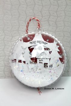 a glass ornament with a house and christmas tree on it's side