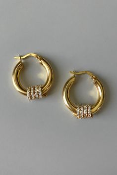 A luxurious and contemporary take on the classic gold hoop, the London earrings are perfect for everyday and high fashion looks. Crafted in 18K gold vermeil, these high polish hoops are designed with a spiral silhouette of continuous white zirconia stones, adding sparkle from every angle. Materials: 18K Gold Vermeil and White ZirconiaDimensions: 20mm hoop, 4mm width What is 18K Gold Vermeil?: 3 microns of 18K Gold over Sterling Silver. Vermeil is far more durable to wear than traditional gold-pl Gold Earrings Everyday, Diamond And Gold Earrings, Traditional Gold Hoop Earrings, 14k Gold Fine Jewelry, Ear Rings Diamond, Silver Gold Plated Jewellery, White Gold Jewellery, Premium Jewelry, High Fashion Looks