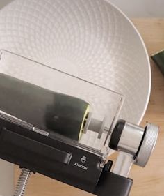 an old camera sitting on top of a wooden table next to a plate and cup