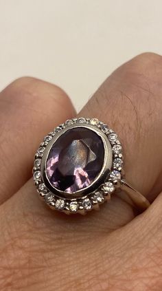 This is a vintage purple amethyst with amethyst sidestones set in 925 sterling We have in size 7 this can be sized to your specification, our jeweler charges $10-$20 please message us to discuss sizing your ring or engraving options. All of our jewelry is hand polished and shipped to you in a stylish gift box. We are happy to gift wrap for you. It is important to us that each customer be thrilled with their purchase. We are grateful for thousands of positive reviews. Heirloom Amethyst Ring With Center Stone, Heirloom Purple Amethyst Ring With Center Stone, Purple Amethyst Gemstone With Center Stone, Formal Lavender Hallmarked Amethyst Ring, Formal Lavender Amethyst Ring Hallmarked, Vintage Silver Amethyst Ring With Accent Stones, Purple Amethyst Ring With Center Round Stone, Classic Rings With Stones For Formal Occasions, Classic Stone Rings For Formal Occasions