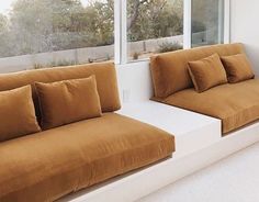 two brown couches sitting next to each other in front of a window