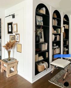 a living room filled with furniture and bookshelves next to a doorway that leads to another room