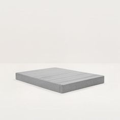 a gray mattress sitting on top of a white floor