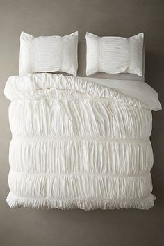 the bed is made with white ruffled sheets and pillowcases on top of it