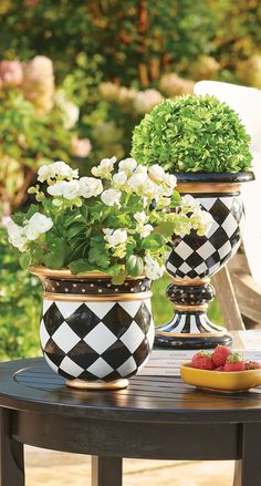 two black and white vases sitting on top of a table with flowers in them