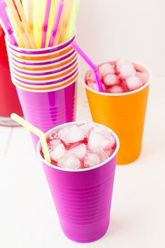 purple cups filled with ice and straws on top of a table