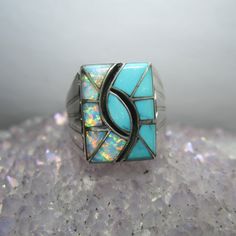 A stunning Opal and Turquoise ring crafted and signed by Navajo silversmith Norman Lee. Ring Size 12.5. The top of the ring measures about 18.8mm x 14mm (.075" x 0.5"). Markings - "N. Lee" and "Sterling" on the inside of the band (pictured). Weight - 13 grams This is a vintage piece in excellent condition. It has been professionally cleaned and sanitized for your peace of mind.  The Trading Post is based in Chardon, Ohio. We carry a large selection of gold and silver jewelry, bullion, numismatic Numismatic Coins, Band Pictures, Ring Crafts, Rings Statement, Turquoise Ring, Sterling Silver Jewelry, Statement Rings, Silver Jewelry, Opal