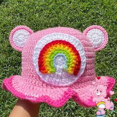 a pink crocheted hat with a rainbow on it and a white bear in the center