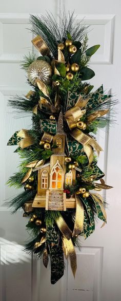 a christmas wreath hanging on the front door with gold and green ribbons, bells and decorations