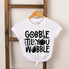 a t - shirt that says gobble it's you wobble hanging on a clothes rack