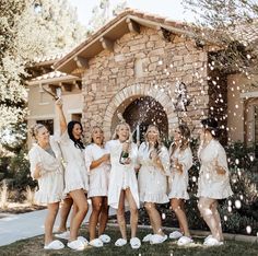 a group of women standing next to each other in front of a house with confetti