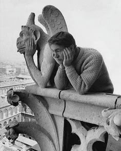 a woman leaning on top of a building while talking on a cell phone