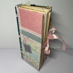 an open book with many different patterns and ribbons on the front, sitting next to a pink ribbon