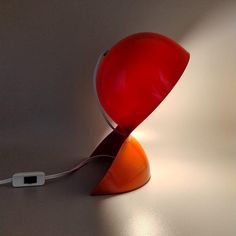 an orange and red lamp sitting on top of a table next to a charger