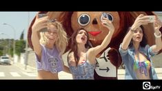 three girls standing next to each other holding up cell phones in front of a large stuffed animal