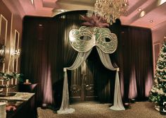 a fancy room decorated for christmas with white drapes and decorations on the door, chandelier and table