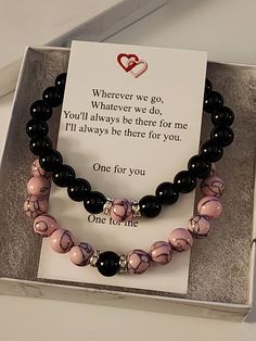 two bracelets with black and pink beads on display in a gift box for someone special