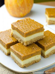 four pieces of cake sitting on top of a white plate next to an orange pumpkin