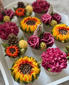 cupcakes decorated with colorful flowers on a white tray, ready to be eaten