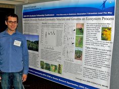 two men standing next to a poster in front of a wall with pictures on it