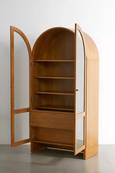 an open wooden bookcase sitting on top of a floor next to a white wall