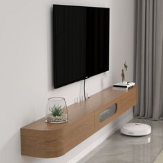 a flat screen tv mounted to the side of a wall next to a wooden shelf