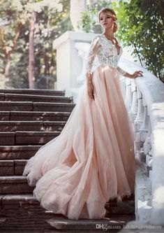 a woman is standing on some steps wearing a long pink dress and posing for the camera