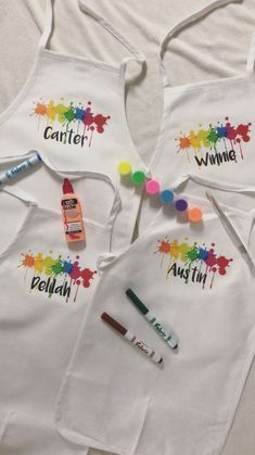 three children's aprons with paint and crayons on them, one for each child