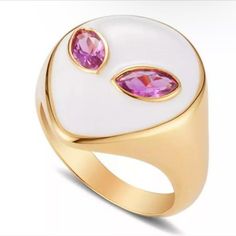 a white and gold ring with two pink stones on the front, one in the middle