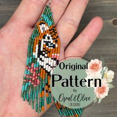 a hand holding a beaded tiger pendant on it's palm, with the words original pattern written below