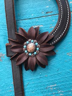 a cowgirl's headband with a flower and beads on the end, sitting on a blue wooden surface