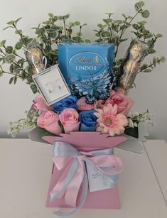 a bouquet of flowers and chocolates in a pink box with ribbon on the table