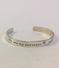 "Bracelet details: - Personalized hand stamped 16 gauge  (really thick and heavy) pure sterling silver - Reads \"You are my sunshine\" and has a tiny sun stamped next to it - Add your children's names or initials after the wording - Comes with a polishing pad to help keep your silver shiny - Shipped in a black velvet gift bag Each letter is individually hand placed and stamped with a hammer, which means no two pieces will be alike. Some letters may be deeper than others, as is the case with all Kids Names, Hand Stamped Jewelry, Sterling Silver Cuff Bracelet, My Sunshine, Stamped Jewelry, You Are My Sunshine, Sterling Silver Cuff, Silver Cuff Bracelet, Silver Cuff