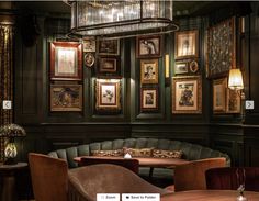 an elegant dining room with green walls and pictures on the wall above the table, along with brown velvet upholstered chairs