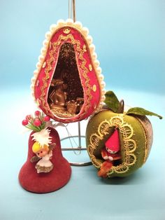 two small figurines sitting next to each other on a blue surface with an apple in the foreground