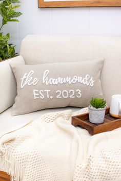 a white couch with a pillow that says the diamonds est 2013 on it and a potted plant next to it